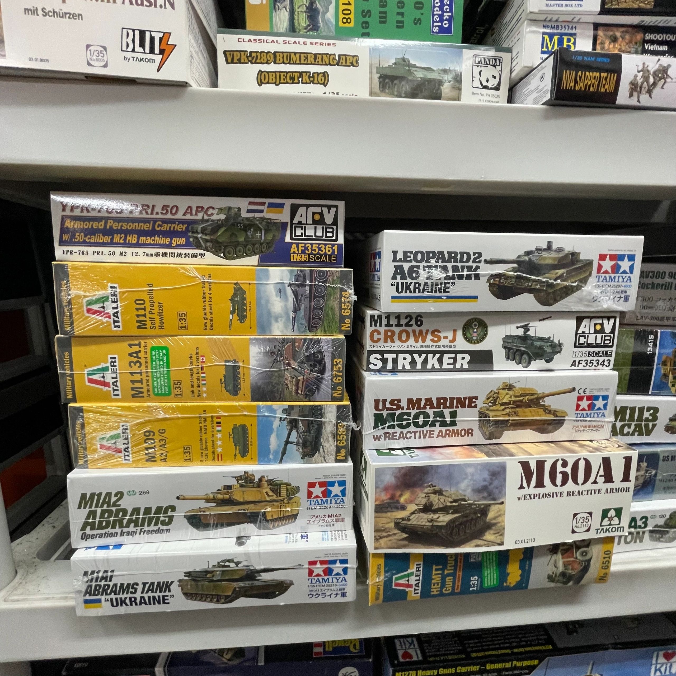 Shelves filled with military model kits featuring tanks and armored vehicles